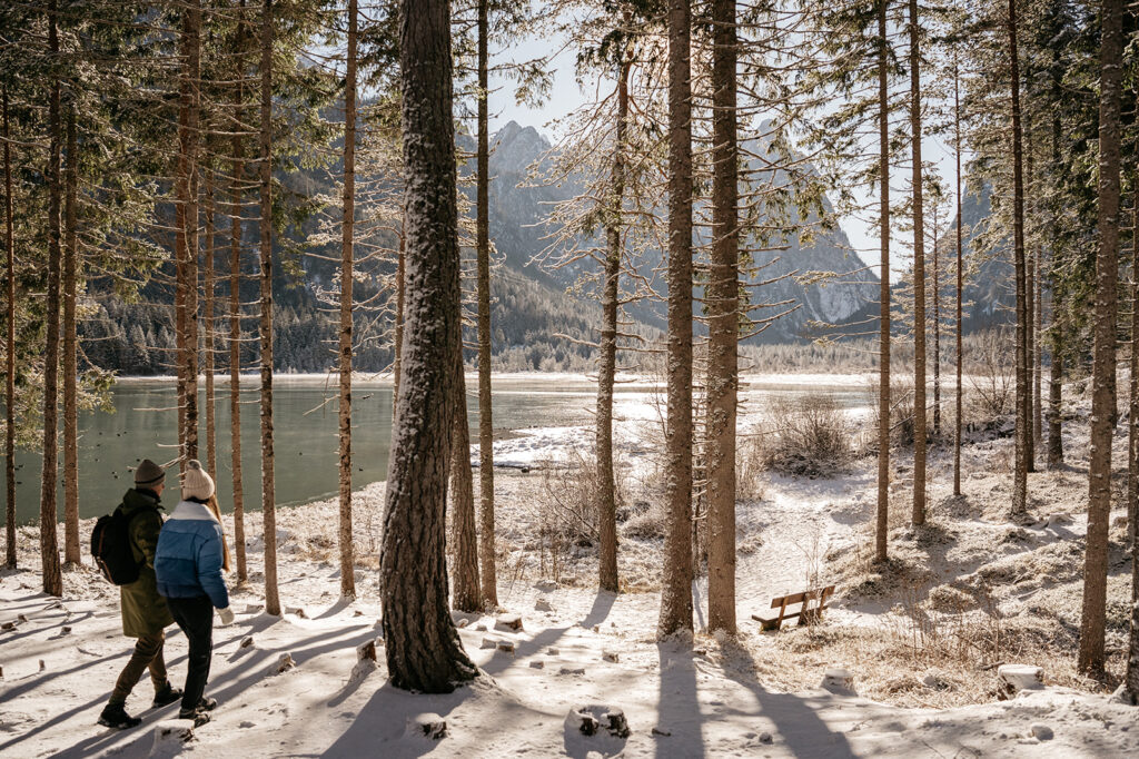 Couple hiking in snowy forest by a lake.