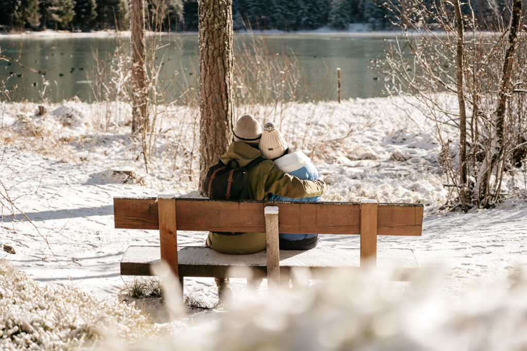 Couple hugging on snowy bench by lake