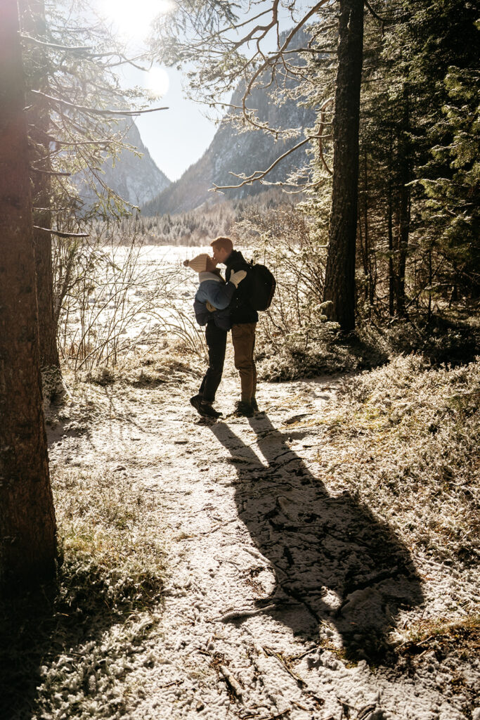 Couple embraces on snowy forest path.