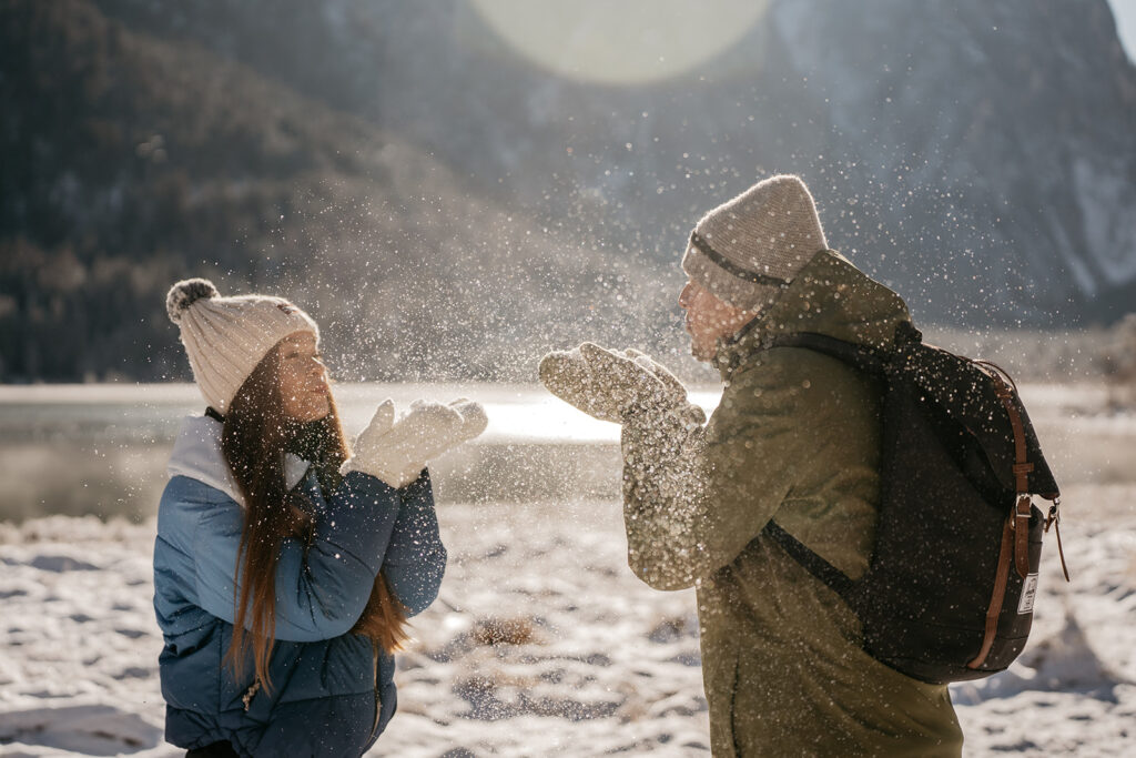 Two people playing with snow in winter gear.