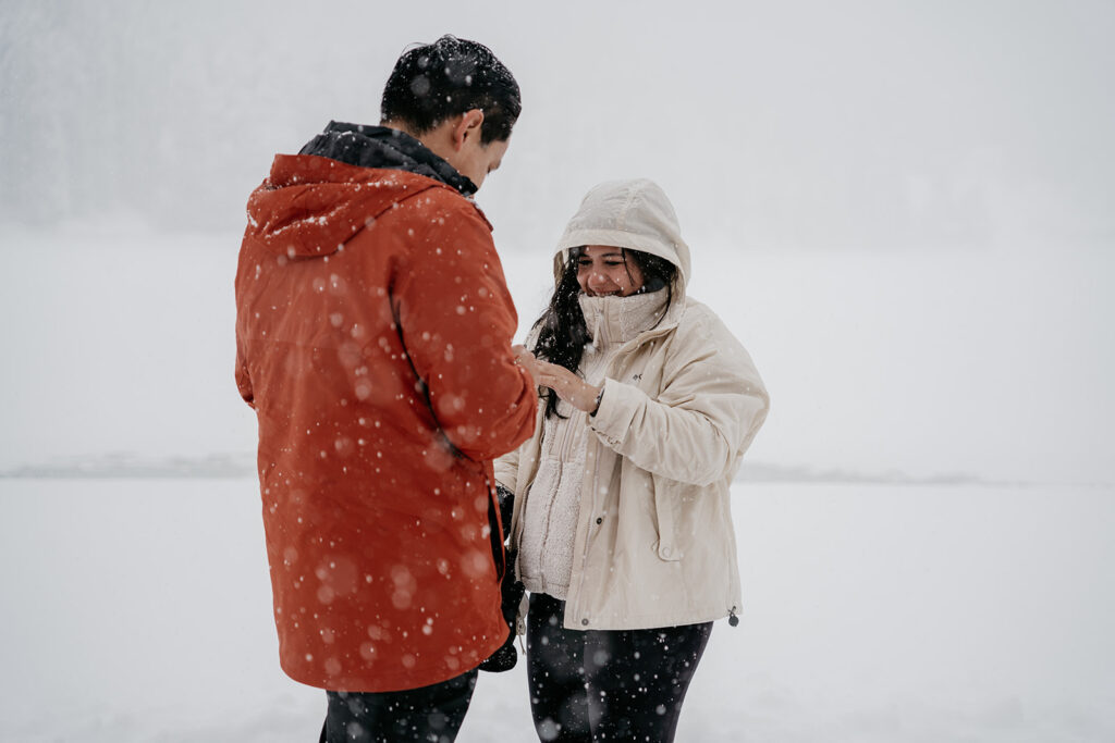 Couple enjoying snowy day in warm jackets.