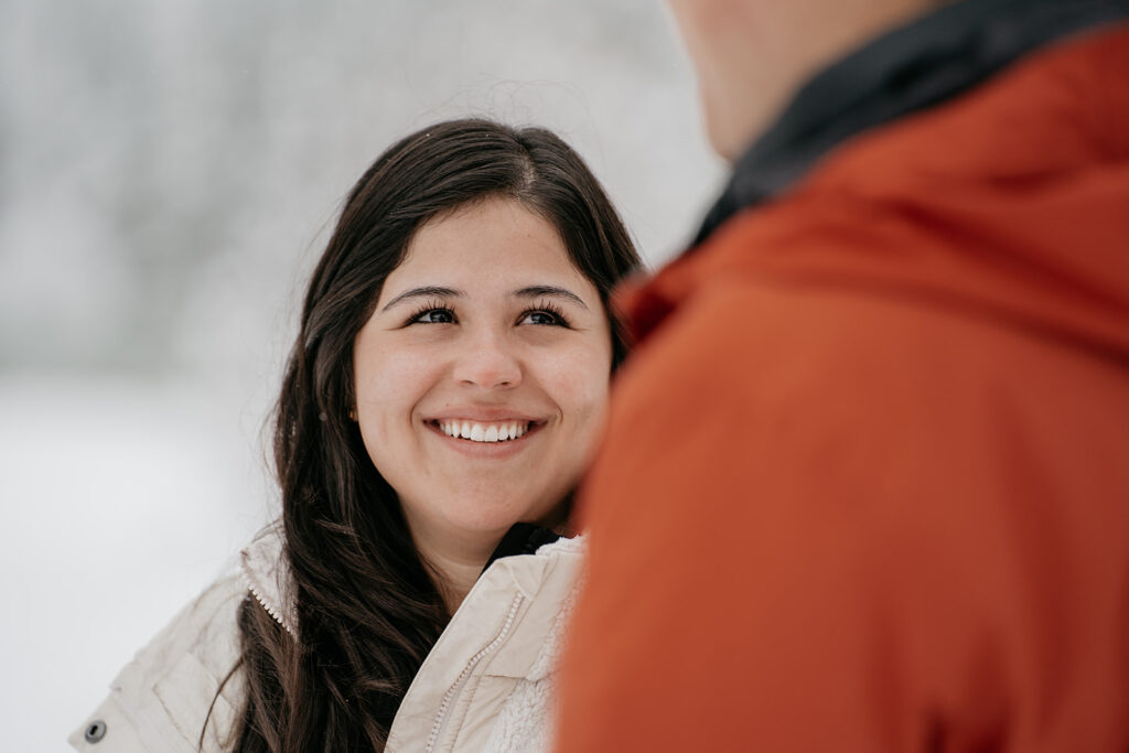 Smiling woman in white jacket outdoors.