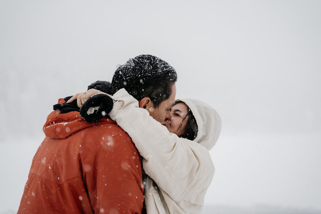 Couple kissing in snowy landscape.