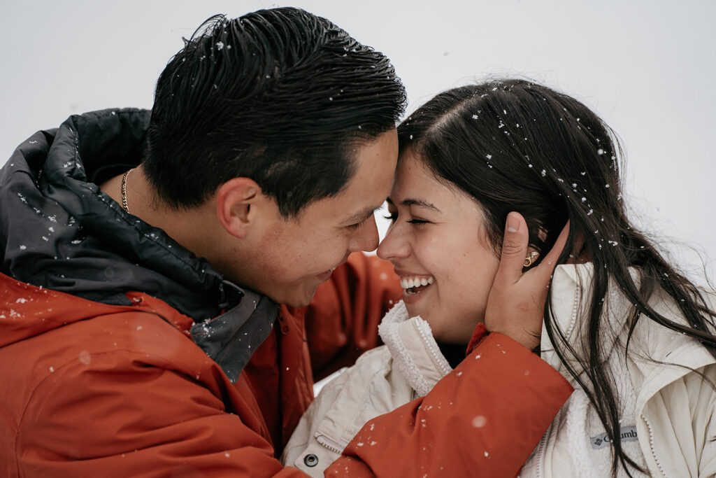 Smiling couple in snow embracing closely