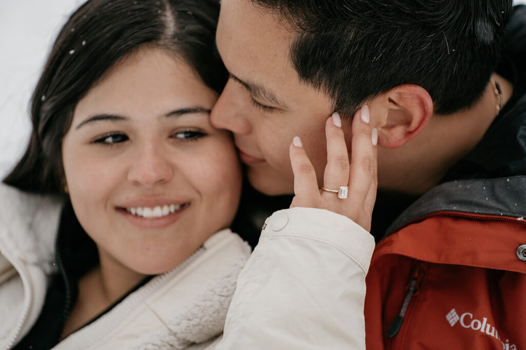 Couple embracing, showing engagement ring close-up.