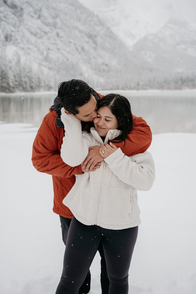 Couple embracing in snowy mountain landscape.