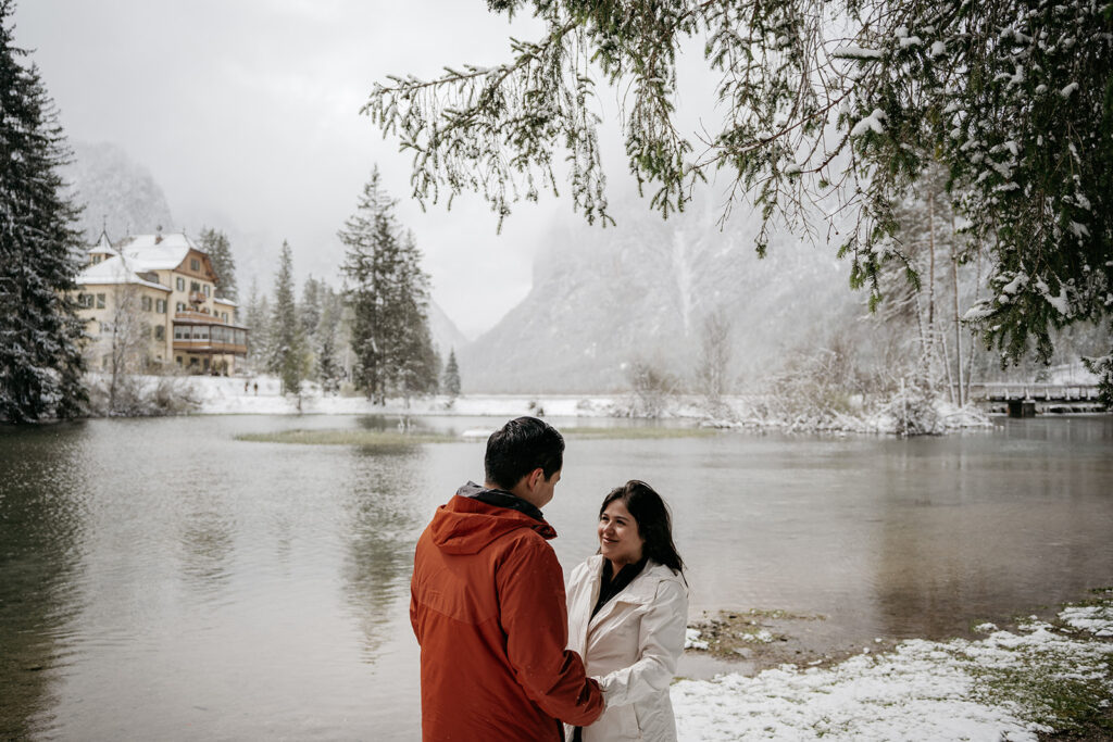 Couple enjoying snowy lakeside scenery together.