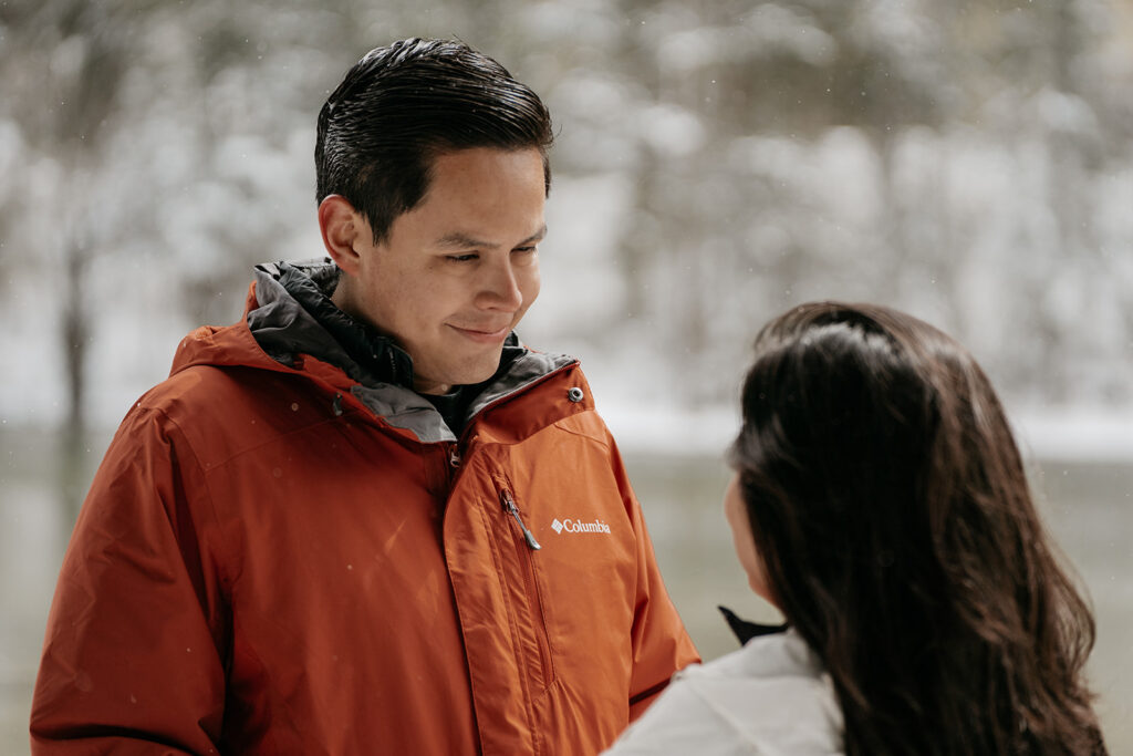 Couple in snow, man in orange jacket.