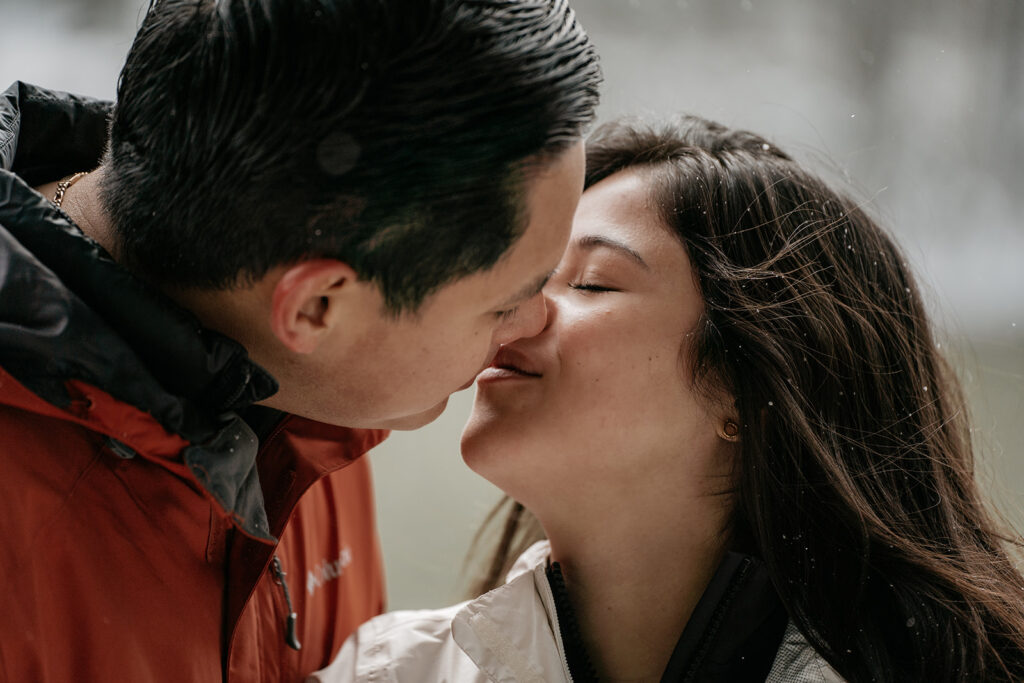 Couple kissing in snowy outdoor setting.