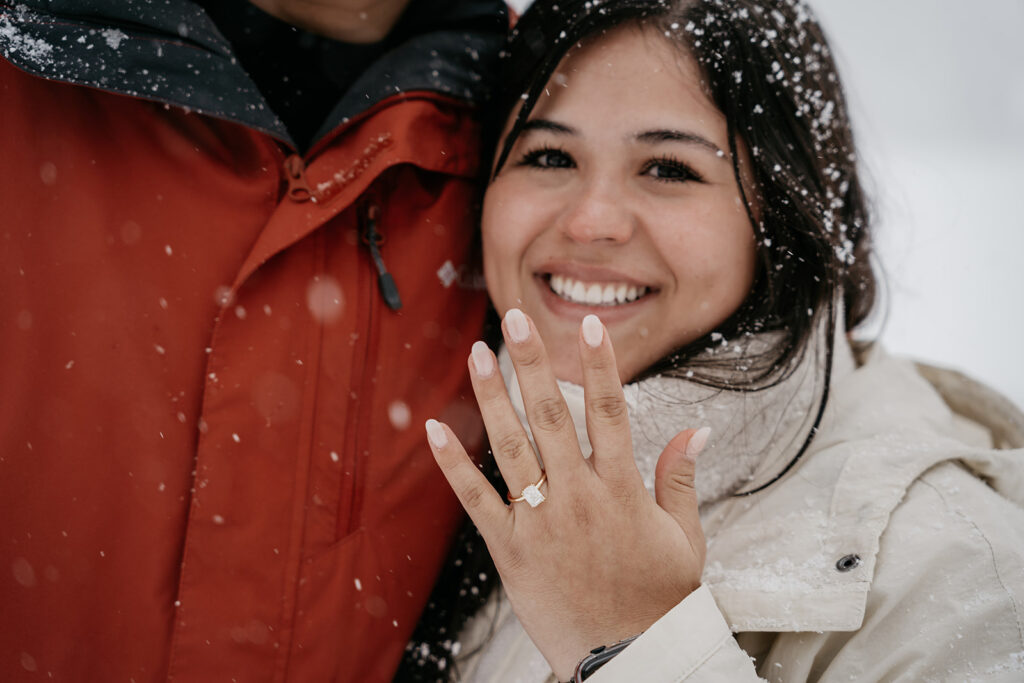 Smiling woman shows off engagement ring in snow