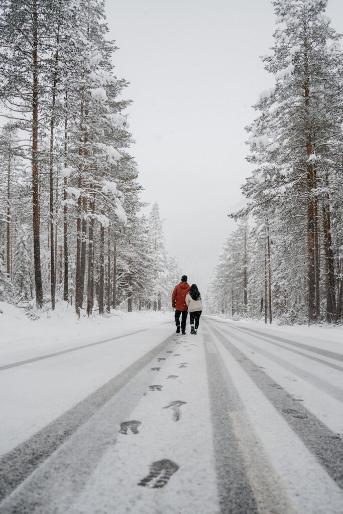 Couple walks on snowy forest road.