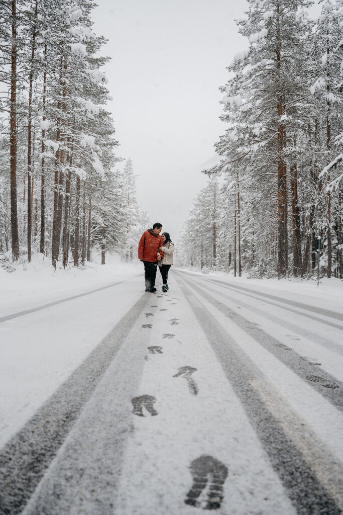 Couple walking on snowy forest road.