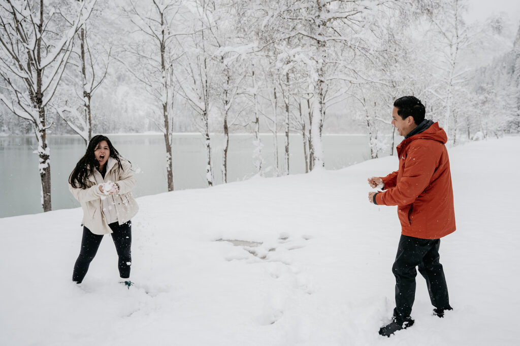 Two people having a snowball fight by lake.