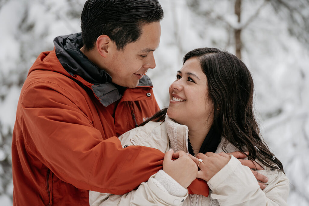 Smiling couple in snowy winter landscape.