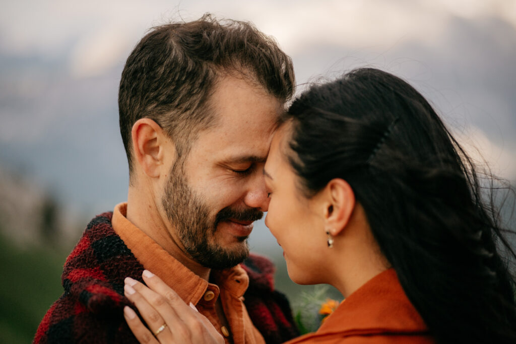 Couple embracing outdoors with mountains background.