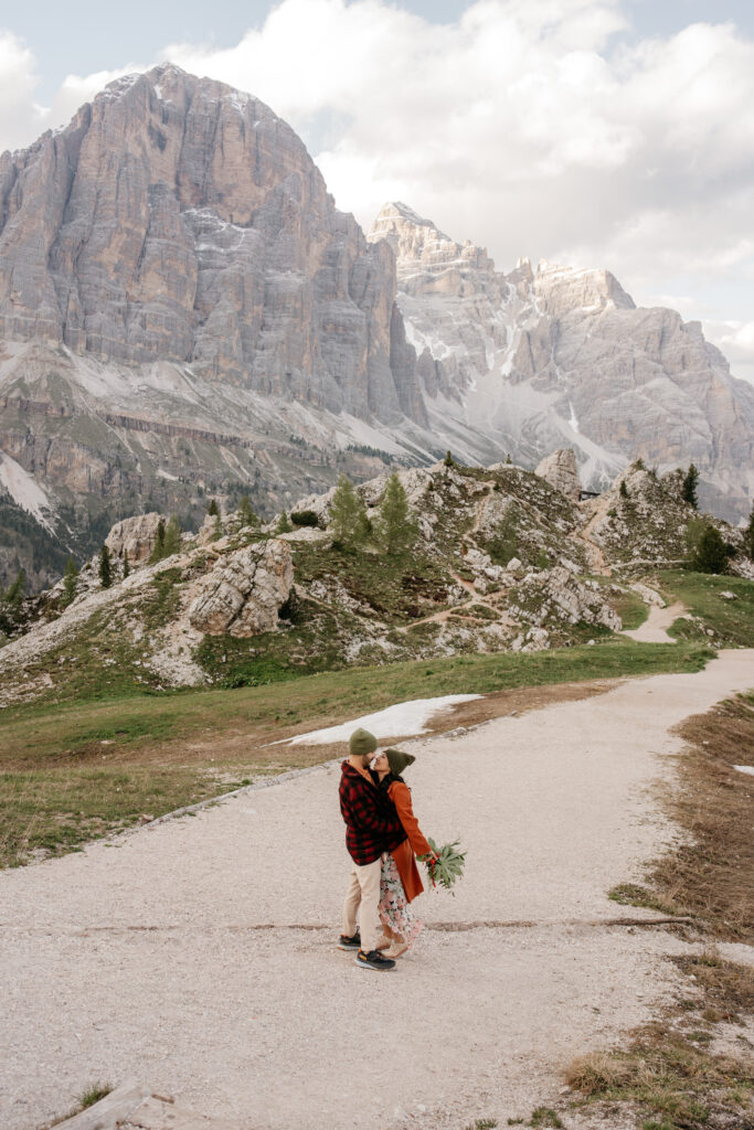 Couple embraces on mountain path, scenic rocky landscape.