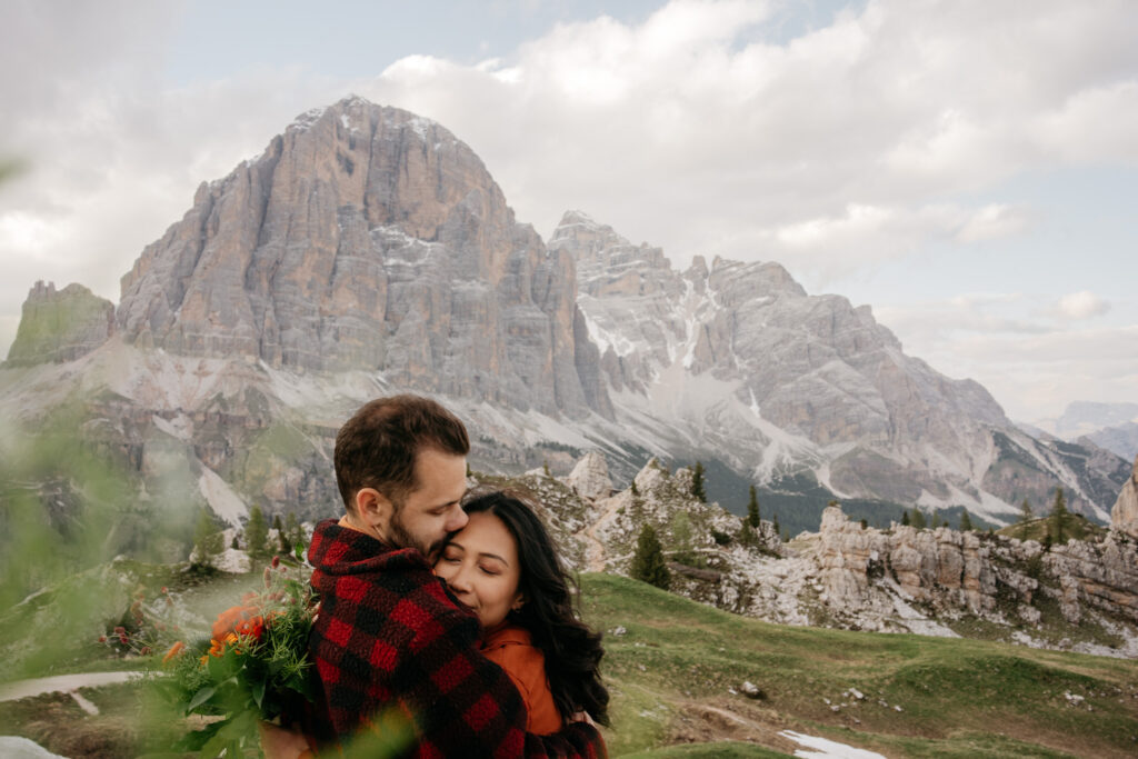 Couple embraces with mountain in background.