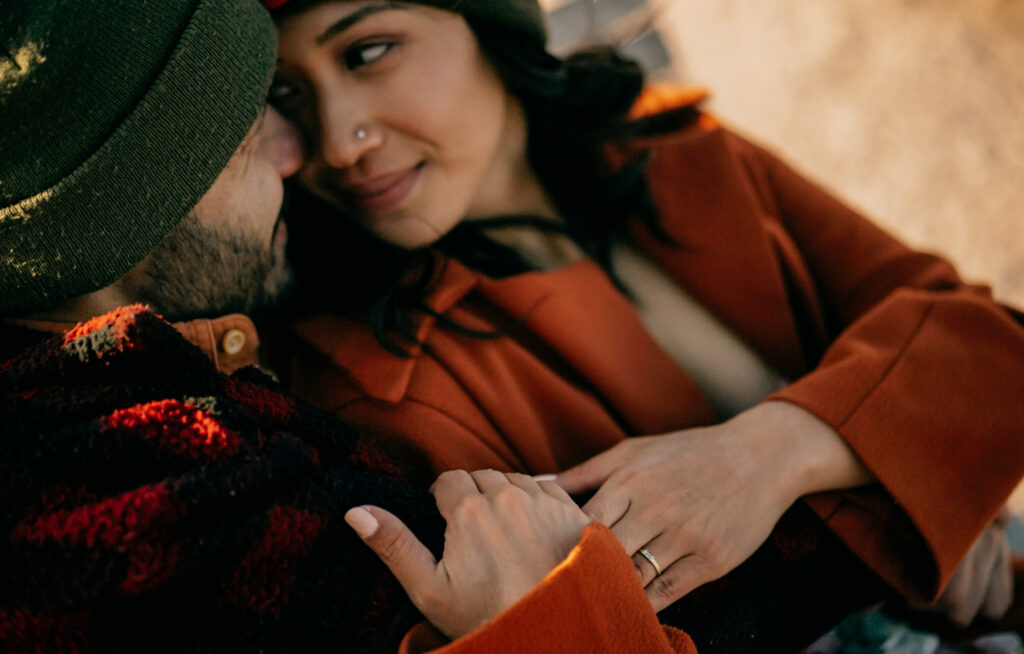 Close-up of couple embracing outdoors, wearing coats.