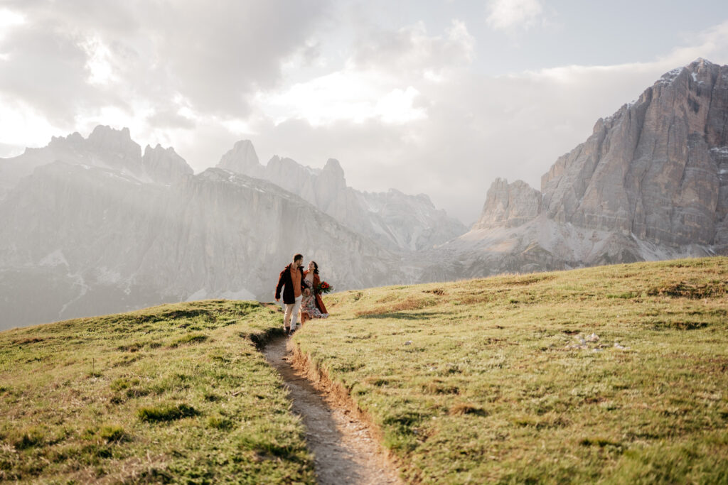 Couple walking scenic mountain path at sunset.