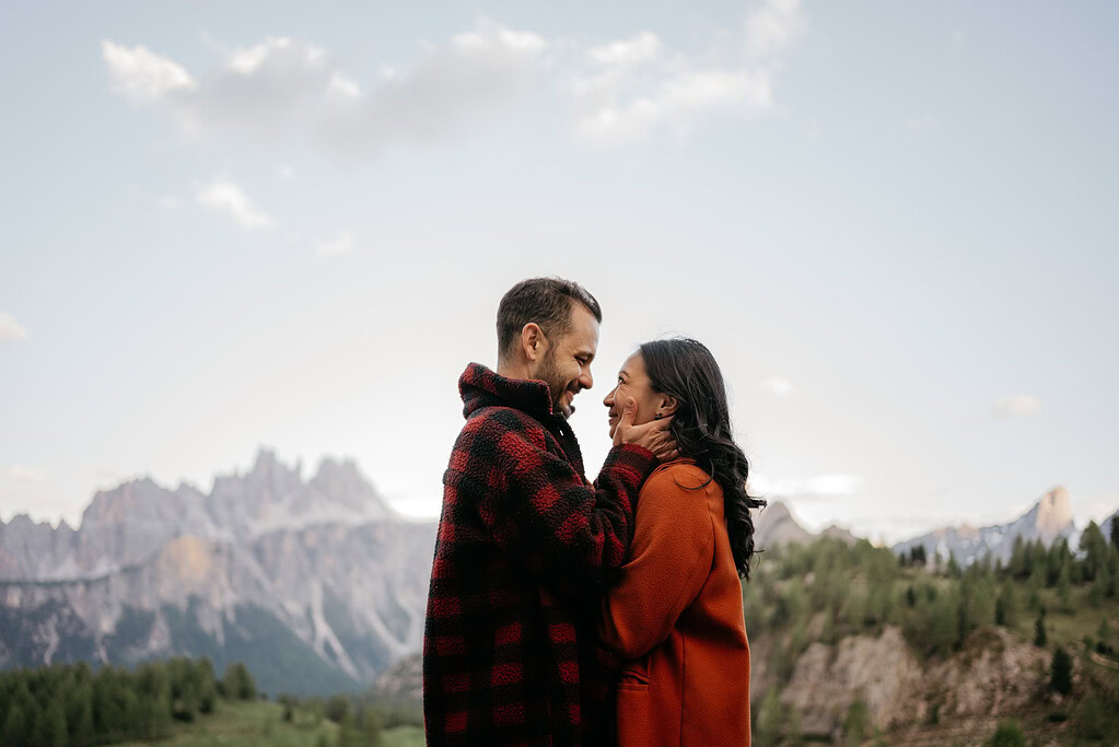 Couple embraces against mountain landscape background.