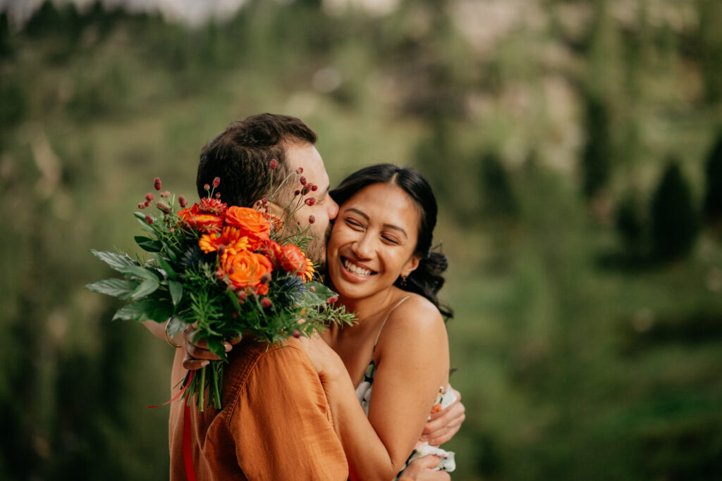 Couple smiling with vibrant orange flower bouquet