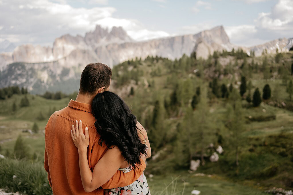 Couple embraces overlooking scenic mountainous landscape.