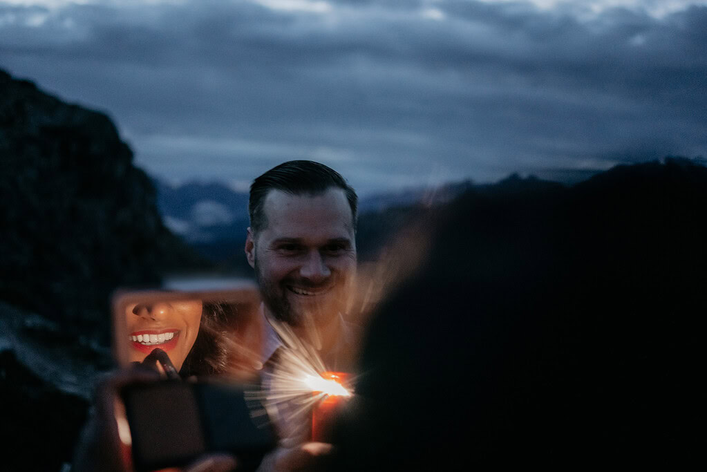 Man smiling with a lit candle outdoors