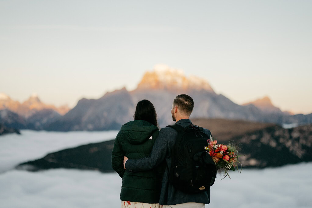 Couple embraces with mountain and cloud view.