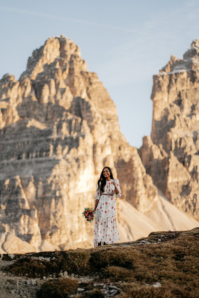 Woman in floral dress, smiling with mountain backdrop