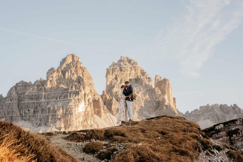 Couple embracing in front of scenic mountain backdrop.