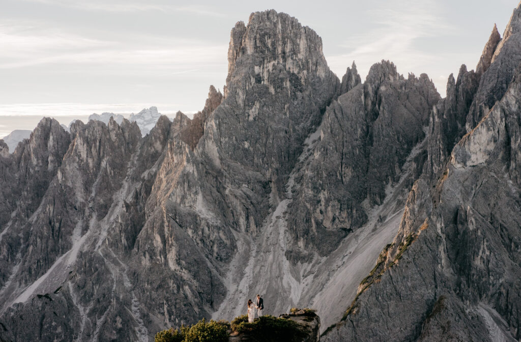 Dramatic mountains with couple on a cliff edge.