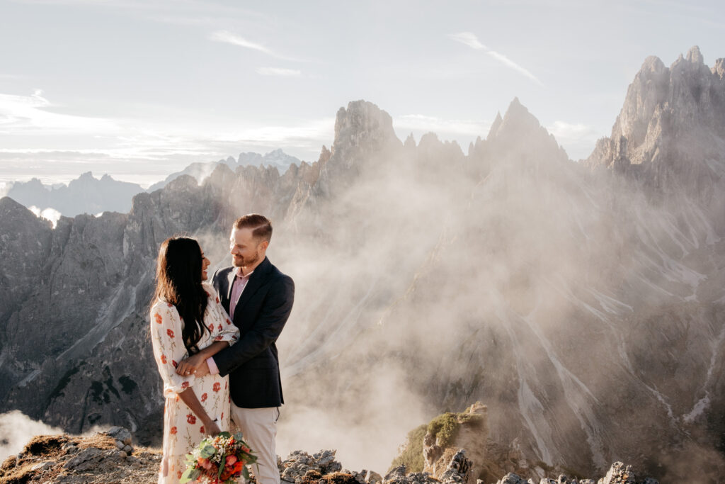 Couple embracing on mountain with misty backdrop