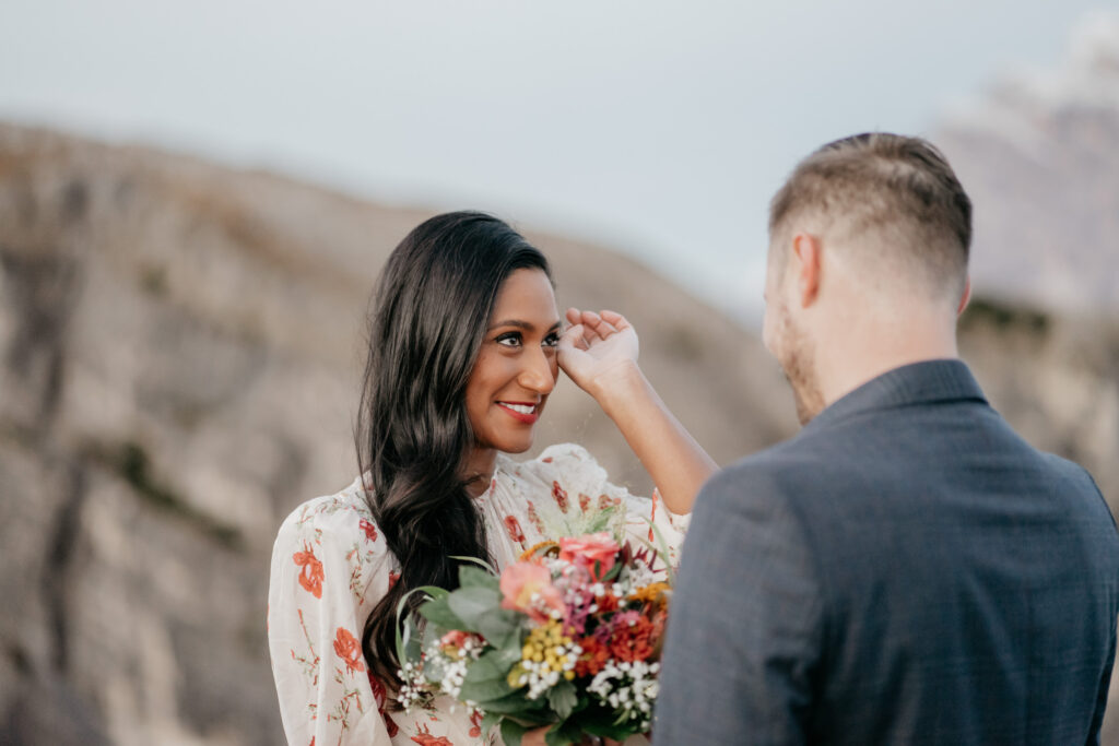 Couple smiling with bouquet in outdoor setting.