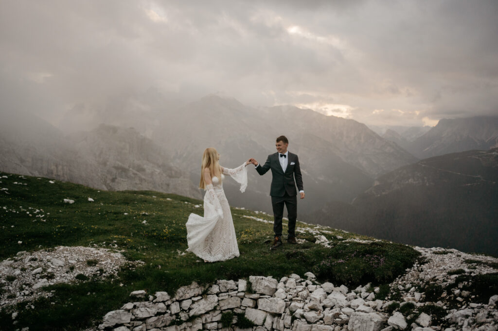 Couple dancing on a mountain in wedding attire.