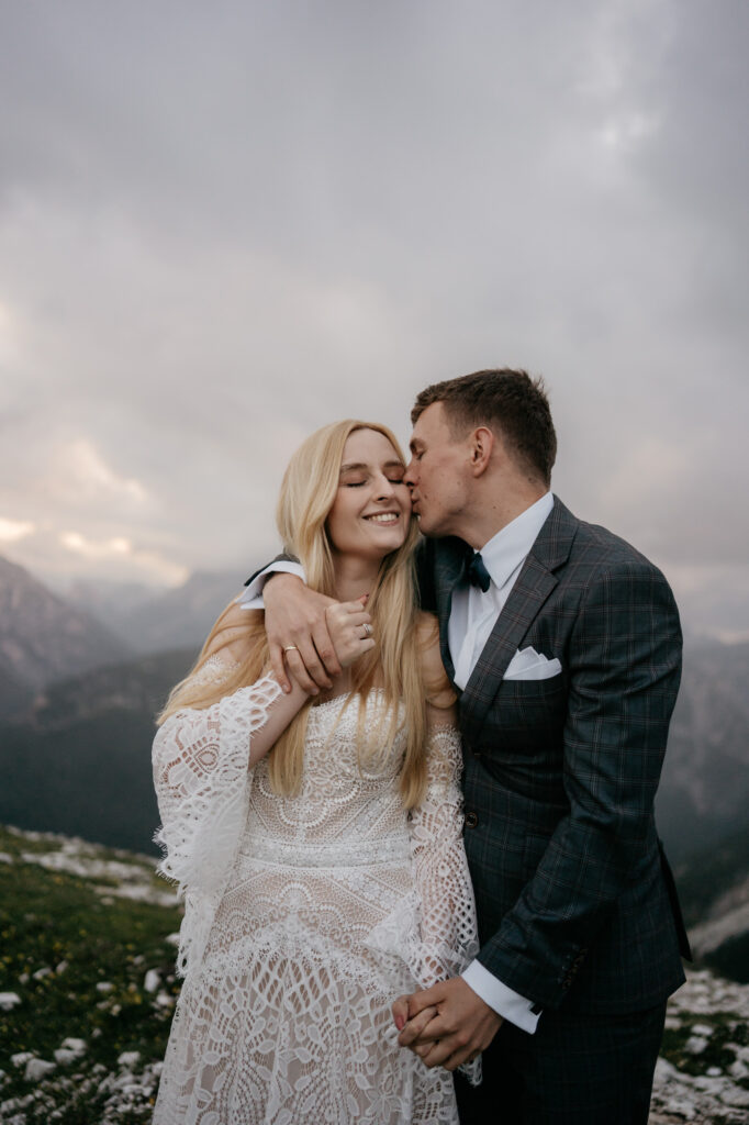 Couple embracing in mountains, wedding attire