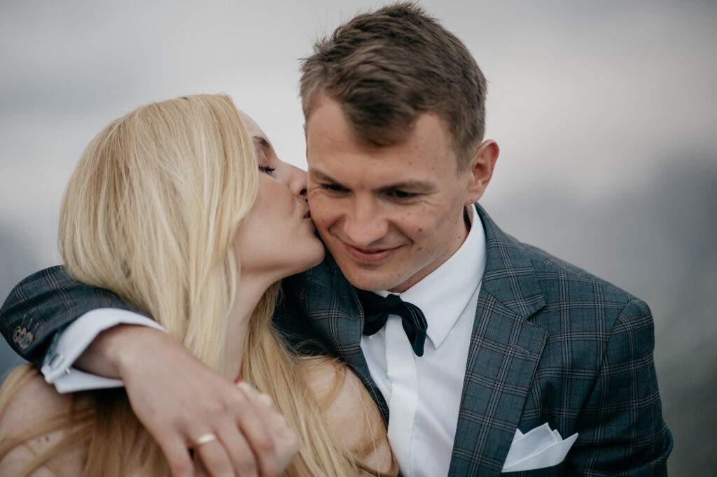 Woman kisses man's cheek lovingly.