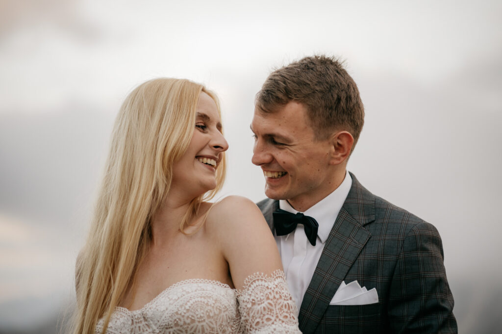 Smiling couple in formal attire, laughing together.