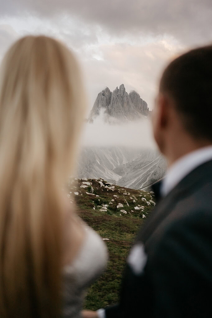 Couple admiring mountain view with cloud cover.