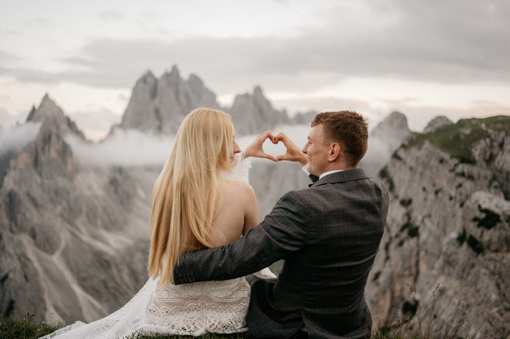 Couple making heart shape in mountain landscape.