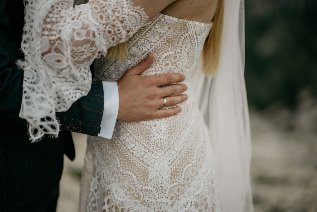 Bride and groom embracing in lace dress.