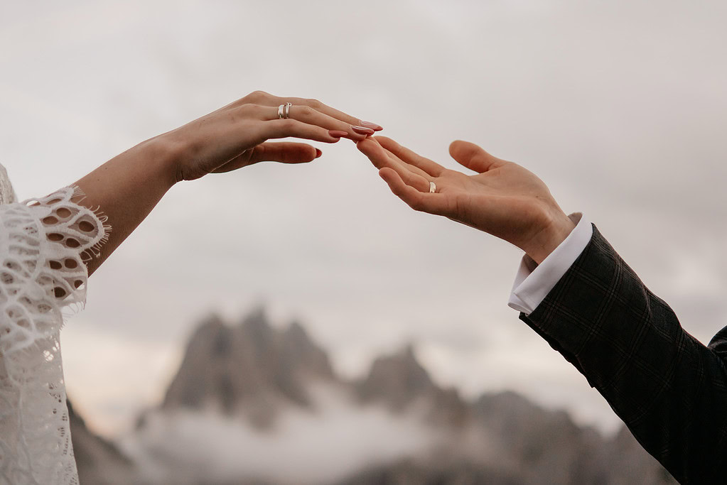 Couple reaching hands with wedding rings sky background