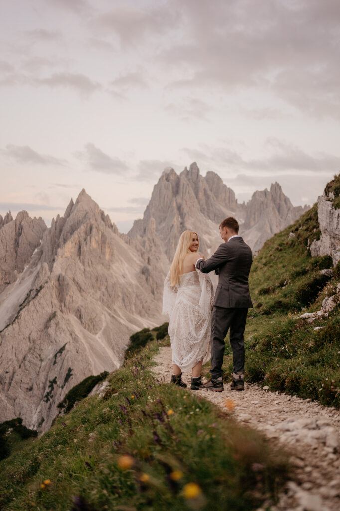 Couple hiking on mountain trail at sunset.