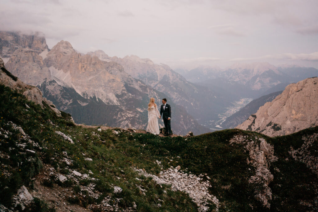 Couple stands on mountain with panoramic view