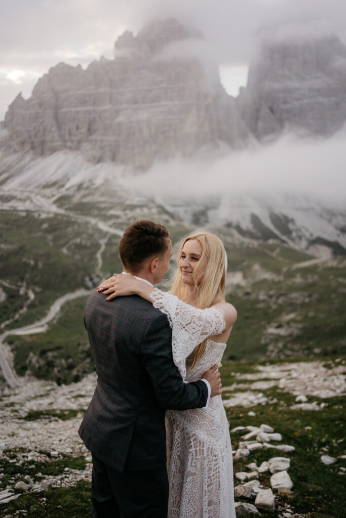 Couple embracing in mountain landscape with misty hills.