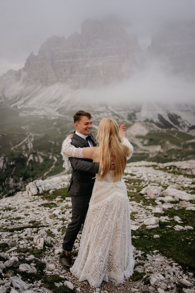 Couple dancing on rocky mountain landscape with fog.