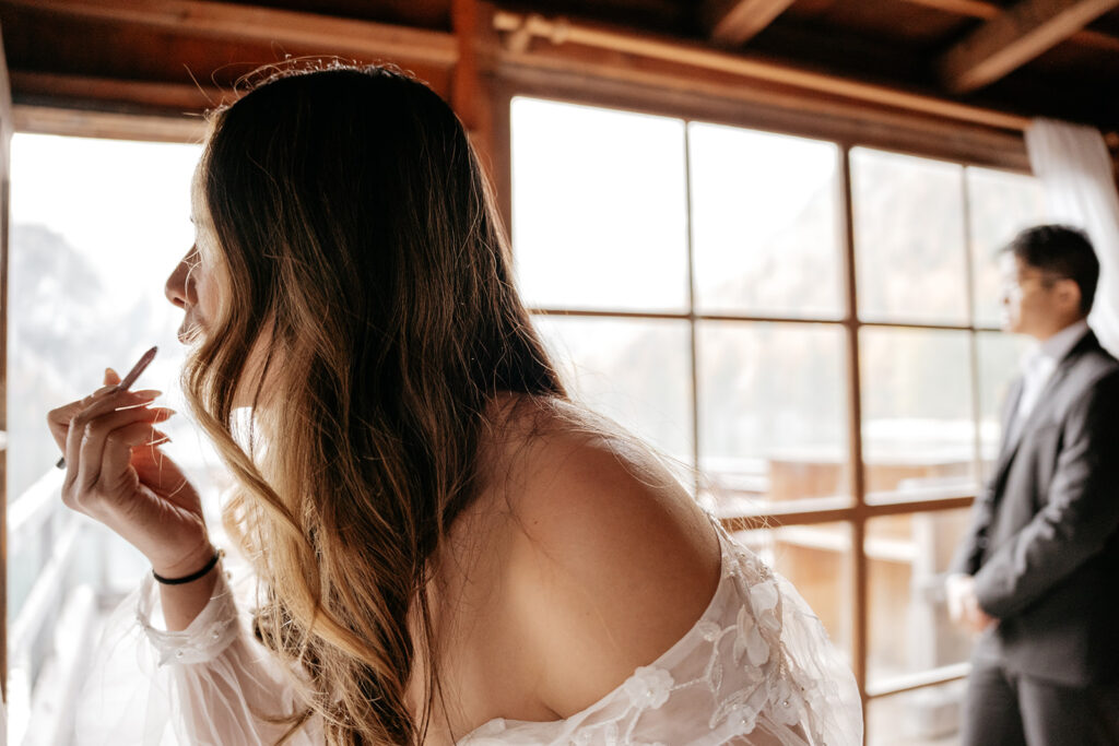 Woman in wedding dress near large window.