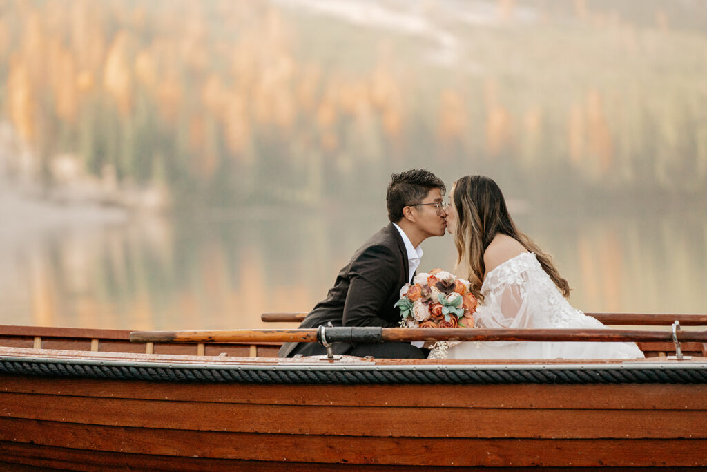 Couple kissing in a boat with bouquet.