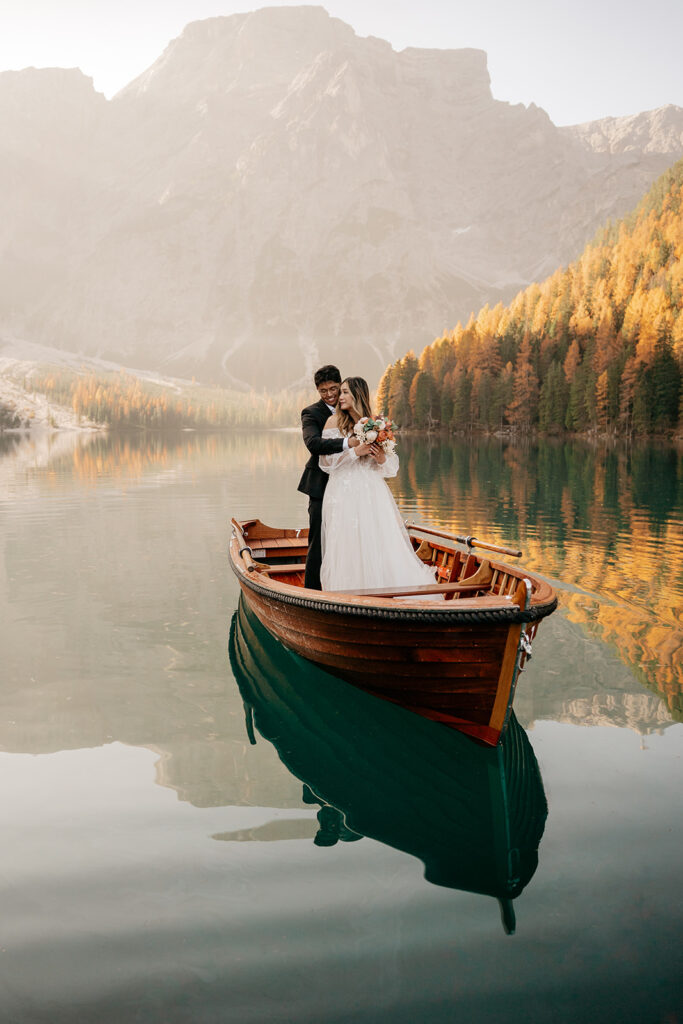 Couple embracing on a boat in scenic mountain lake.