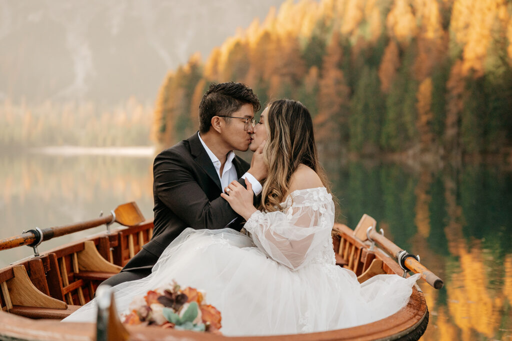 Couple kissing on a boat, autumn lake background.