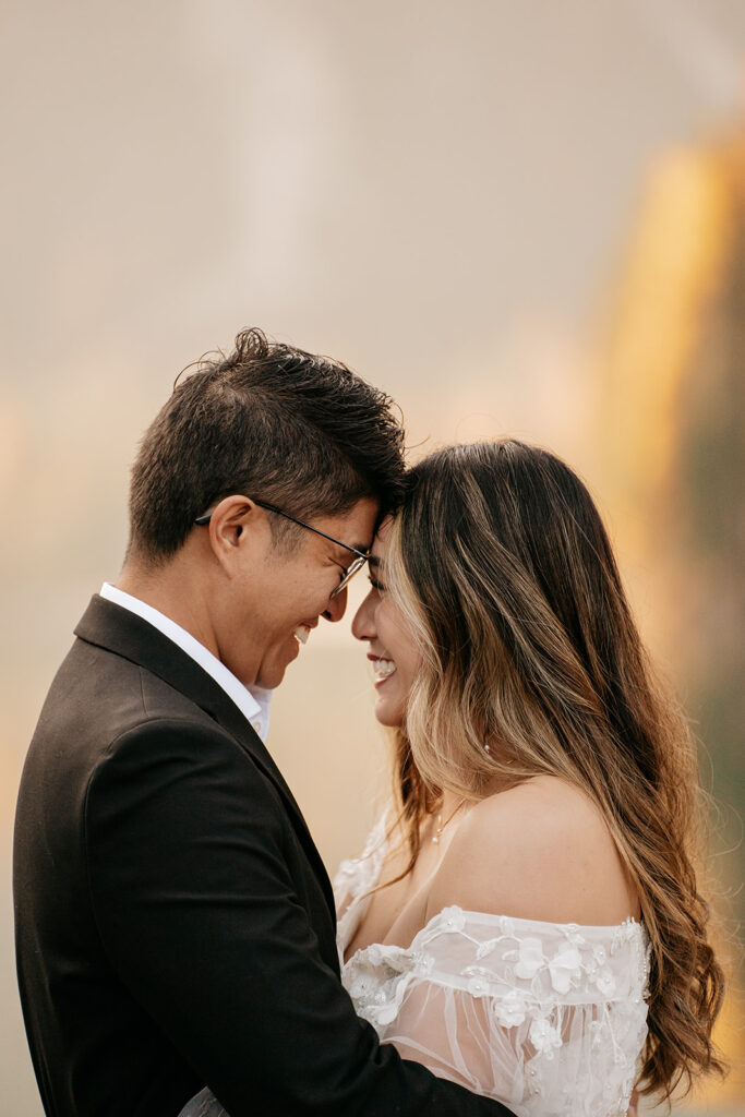 Smiling couple in formal attire embracing closely.